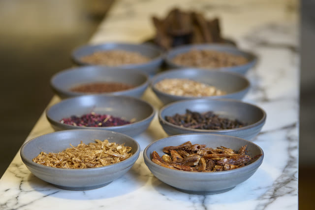 Small bowls of grains and spices arranged on a pale marble counter.