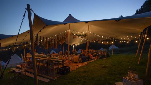 The same tent from a different angle, fully lit against the darkening sky and mountains.