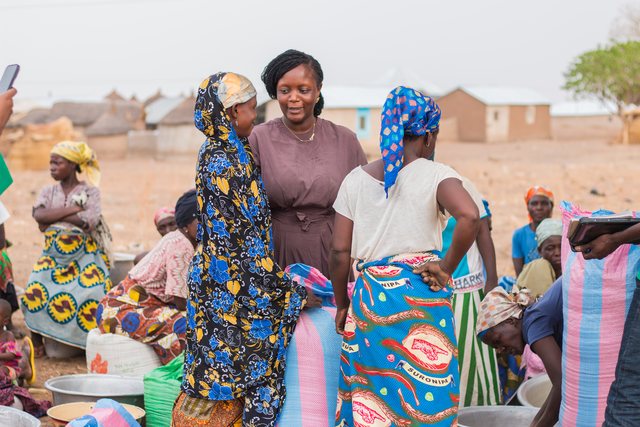 A group of women in colorful dress gather together in a village setting.